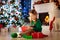 Child opening present at Christmas tree at home. Kid in elf costume with Xmas gifts and toys. Little girl with gift box and candy