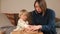 Child opens gift in front mother She unfolds scroll, touches it with her hands