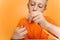 Child in an orange T-shirt tries to insert a thin strip of paper into a quilling tool