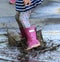 Child outdoor jump into puddle in boot after rain