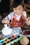 Child painting ceramic pot with paint brush