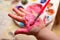 Child painting her hand with pink paint