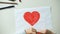 Child painting red heart, putting love word made of wooden cubes on sides