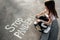 The child paints with chalk on the asphalt, a little girl writes inscription - stop pandemic