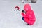 A child photographs a snowman with a phone na outdoors in the forest