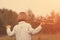 Child pilot aviator with plane at sunset, little boy playing with cardboard toy airplane outdoors, against summer sky background.