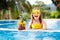 Child with pineapple in swimming pool. Kids swim