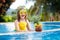 Child with pineapple in swimming pool. Kids swim