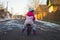 Child in pink jumpsuit rides balance bike on dirt road in countryside