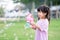 Child play with the bubble gun and have fun. Happy children standing in the grass. Sweet smile of a little girl. Time to relax.