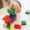 Child play with colored wooden brick shapes