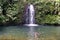 Child playing below a waterfall in the jungle in Ecuador