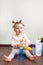 Child playing with bottles with household chemicals sitting on the floor of the house.