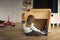 Child playing with a cardboard playhouse