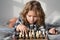 Child playing chess on bed. Clever child thinking about chess. Kids early development.