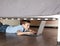 Child playing laptop under the bed