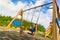 Child playing on outdoor playground in rain. Kids play on school or kindergarten yard. Active kid on colorful swing. Healthy