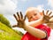 Child playing outdoor showing dirty muddy hands.