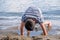 Child playing sands head down on the beach. One little Asian boy in casual clothing beside water in Switzerland