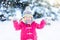 Child playing with snow in winter. Kids outdoors.