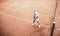 Child playing tennis on outdoor clay court. Top view of little tennis player on open tennis court. Full length shot of sporty