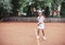 Child playing tennis on outdoor court. Little girl with tennis racket and ball in sport club