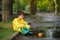 Child playing with toy boat in puddle. Kid play outdoor by rain. Fall rainy weather outdoors activity for young children. Kid