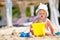 Child playing on tropical beach. Little girl digging sand at sea shore. Kids play with sand toys. Travel with young children