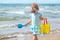 Child playing on tropical beach. Little girl digging sand at sea shore. Kids play with sand toys. Travel with young children