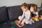 child plays board game at home on couch. sisters are sitting on sofa.