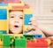 Child plays with construction bricks. Boy holds toy house