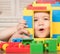 Child plays with construction bricks. Boy holds toy house