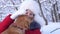 Child plays with his pet on Christmas holidays in the forest. Beautiful girl smiles, caresses her beloved dog in winter