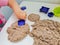 Child plays with kinetic sand: closeup of a child`s hand and sand.