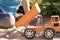 A child plays in the sand with big toy cars, an excavator, a truck