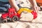 A child plays in the sand with big toy cars, an excavator, a truck