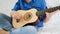 A child plays a small guitar close up. Playing the guitar, singing, music, education, rhythm.