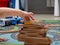 a child plays a wooden railway sitting on the floor. educational games for children. children`s hands close up.