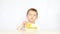 A child with pleasure eating potato chips sitting at a table on a white background