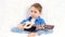 A child with pleasure plays an acoustic guitar sings a song sitting on a white sofa