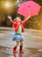 Child with polka dots umbrella wearing red rain boots