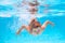 Child in pool in summer day. Child swimming underwater in swimming pool. Funny kids boy play and swim in the sea water.