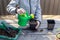 Child pours water from a watering can seedling pot with seeds of plants, standing on a wooden table.