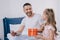 Child presenting fathers day gift box to happy smiling daddy