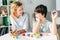 Child psychologist looking at kid with dyslexia and sitting at table with building blocks