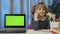 Child pupil schoolgirl at home sitting with digital laptop computer with green screen chroma key