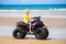 Child on quad bike at beach. All-terrain vehicle.