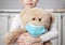 Child on quarantine due epidemic of coronavirus COVID-19. Child girl cuddle toy bear wear medical mask