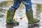Child with rain boots jumps into a puddle
