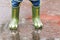 Child with rain boots jumps into a puddle